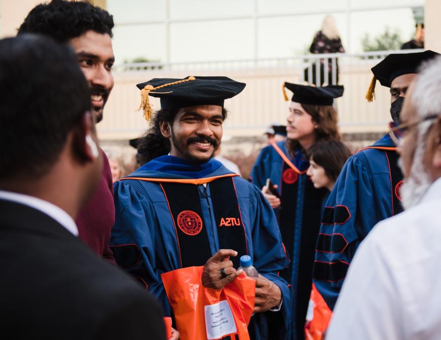 Student in a doctoral hood smiling at his parent